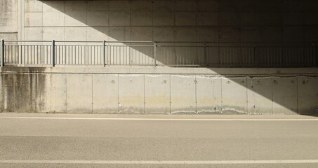 Concrete block wall of an underpass with a footpath and a railing in the middle. Side light and...