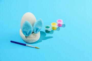 Easter egg painting set with bunny. Brush and paints on light blue background