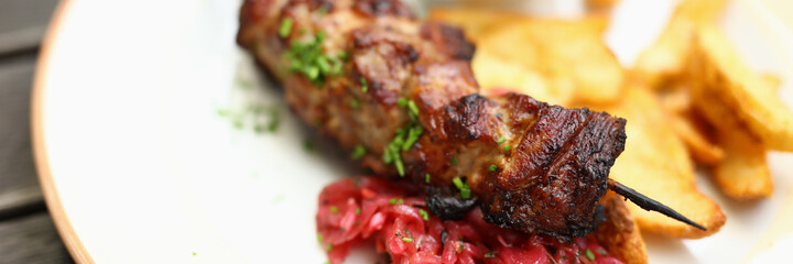 On plate there is kebab potato salad and there is ketchup next to it. Lunch menu concept