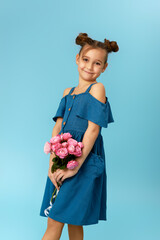 adorable happy little girl holding bouquet of pink roses on blue background.