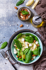 Couscous salad with pear, spinach, almonds, feta cheese and vinaigrette sauce on a gray stone table. Top view flat lay. Copy space.
