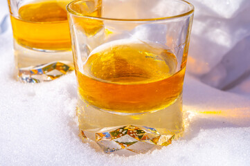 Glasses of cold scotch single malt whisky on white snow