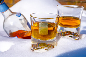 Glasses of cold scotch single malt whisky on white snow