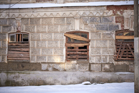 Three windows boarded up with pieces of logs