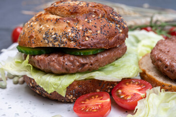 Making tasty vegetarian vegan hamburger from plant based soya beans burger, organic bun with seeds and fresh vegetables