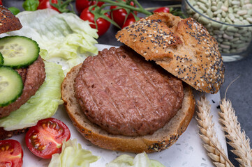 Making tasty vegetarian vegan hamburger from plant based soya beans burger, organic bun with seeds and fresh vegetables