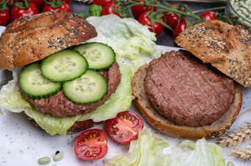 Making tasty vegetarian vegan hamburger from plant based soya beans burger, organic bun with seeds and fresh vegetables