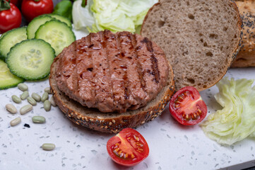 Making tasty vegetarian vegan hamburger from plant based soya beans burger, organic bun with seeds and fresh vegetables