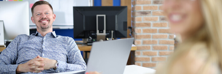 Man manager at work table sits smiling together with colleague. Sales development manager concept