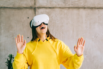 Young amazed caucasian woman using VR headset, gesturing and looking up in virtual reality.