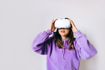 Young caucasian woman using VR headset, touching glasses and looking up in virtual reality on white background.