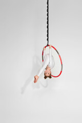 little child girl gymnast in white sportwear shows an acrobatic performance on an aerial hoop © Rychko Yevhen