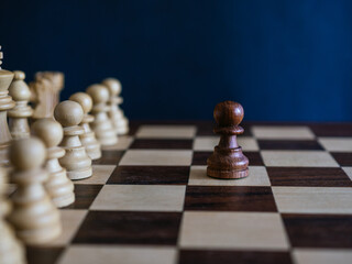 Wooden pawn alone against white set of pieces