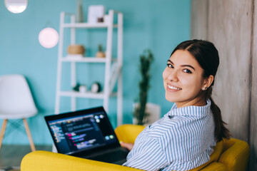 Portrait of young woman mobile developer with laptop, writes program code on a computer, programmer...