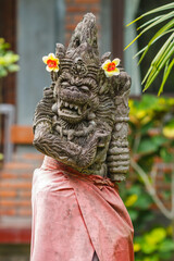 Traditional demon guard statue carved in stone in Bali island.