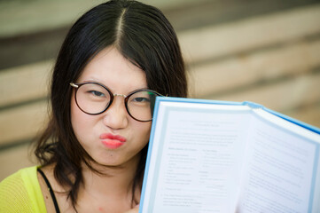 Asian woman in nerd student style reading - lifestyle portrait of young sweet and happy Korean girl...