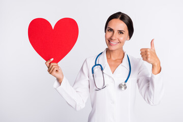 Photo of sweet charming young woman medic back wear formal coat holding red paper heart thumb up isolated white color background