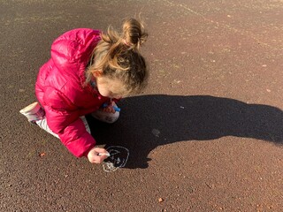 Niña dibujando en el suelo con tizas de colores