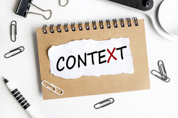 Context . text on white paper over white background. notebook, pen.