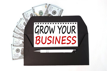 Grow your business. text on white paper on black envelope near money bills