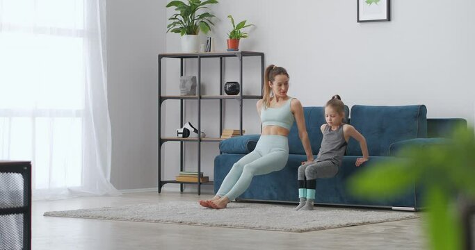 gymnastics and physical exercises of little girl and her sporty mother in living room, healthy lifestyle and good habit