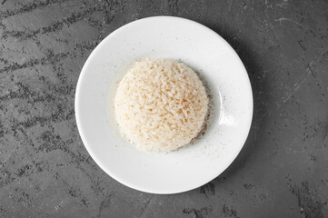 plain white rice with spices on a white plate on a gray concrete background. Top view