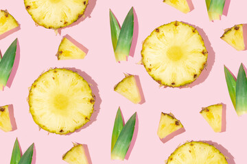 Creative pattern made with pineapple slices and green leaves on pastel pink background. Minimal flat lay. Creative idea with fruits. Spring or summer concept.
