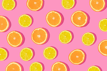 Creative pattern made with orange and lemon slices on bold pink background. Minimal flat lay. Spring or summer trendy concept. Fun idea with citrus fruits.