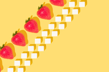 Creative pattern made with strawberries and sugar cubes on bright yellow background. Retro style aesthetic. Minimal trendy idea with fruits. Spring or summer concept. Trendy copy space