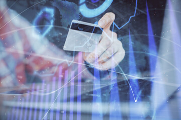 Double exposure of man hands holding a credit card and Forex graph drawing. Stock trading and digital fintech in Internet E-commerce concept.