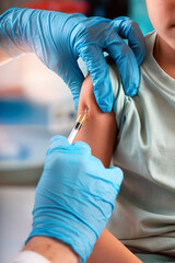 Pediatrician doctor with an injection in the hand for the vaccination of a child. Doctor vaccinating a boy in the pediatric clinic. 