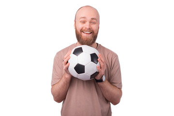 joyful smiling bearded hipster man holding soccer ball and looking at the camera