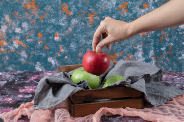 Apples in a rustic wooden tray on the textured background