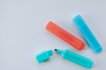 three highlighters on a white sheet of paper in orange, blue and light blue