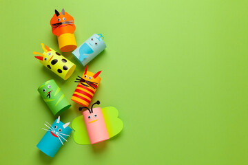 Homemade figures of animals from rolls of paper on green background. Creative kids toys, zero...