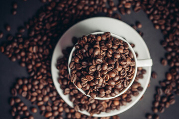 coffee beans in a cup and white saucers gray background close-up
