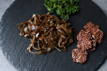 Seaweed, basil on a black slate plate. Healthy food.