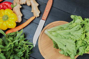 Carrot, pepper, chili, ginger, lettuce with knife on the dark background