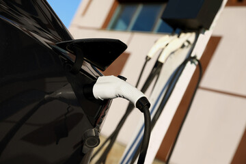 Charging modern electric car from station outdoors, closeup