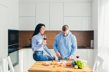 A young couple in love, a man and a woman, are cooking dinner together and having fun in a new apartment