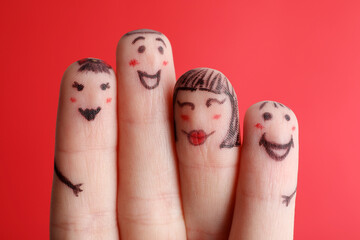 Four fingers with drawings of happy faces on red background