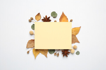 Flat lay composition with autumn leaves and blank card on white background, space for text