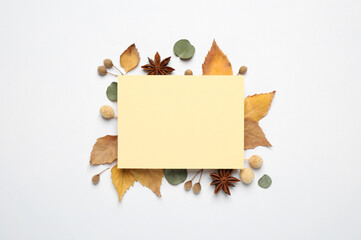 Fototapeta premium Flat lay composition with autumn leaves and blank card on white background, space for text