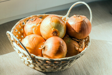 wicker basket with onions, close-up, stands on the table