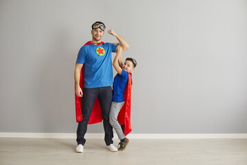Portrait of family with super powers. Happy young dad and little child dressed as superheroes...