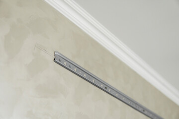 Close-up of stainless steel mounting rail for mounting kitchen cabinets on a wall.