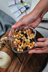 Hand holding a small plate with nuts on the wooden board