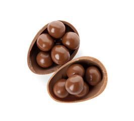 Halves of tasty chocolate egg with candies on white background, top view