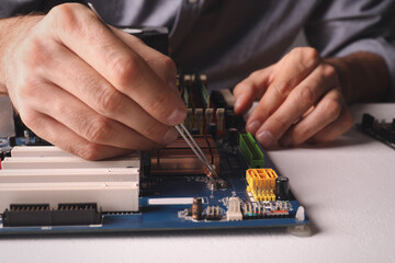 Technician repairing electronic circuit board at table, closeup