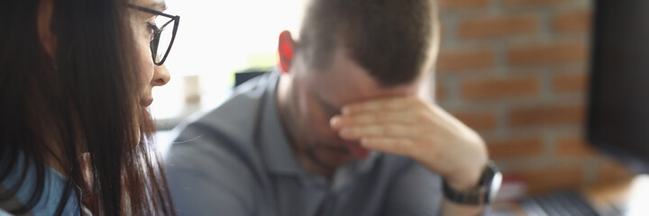 Woman scolds colleague for be late to work. Man regret that he make mistake and sit sad with his...